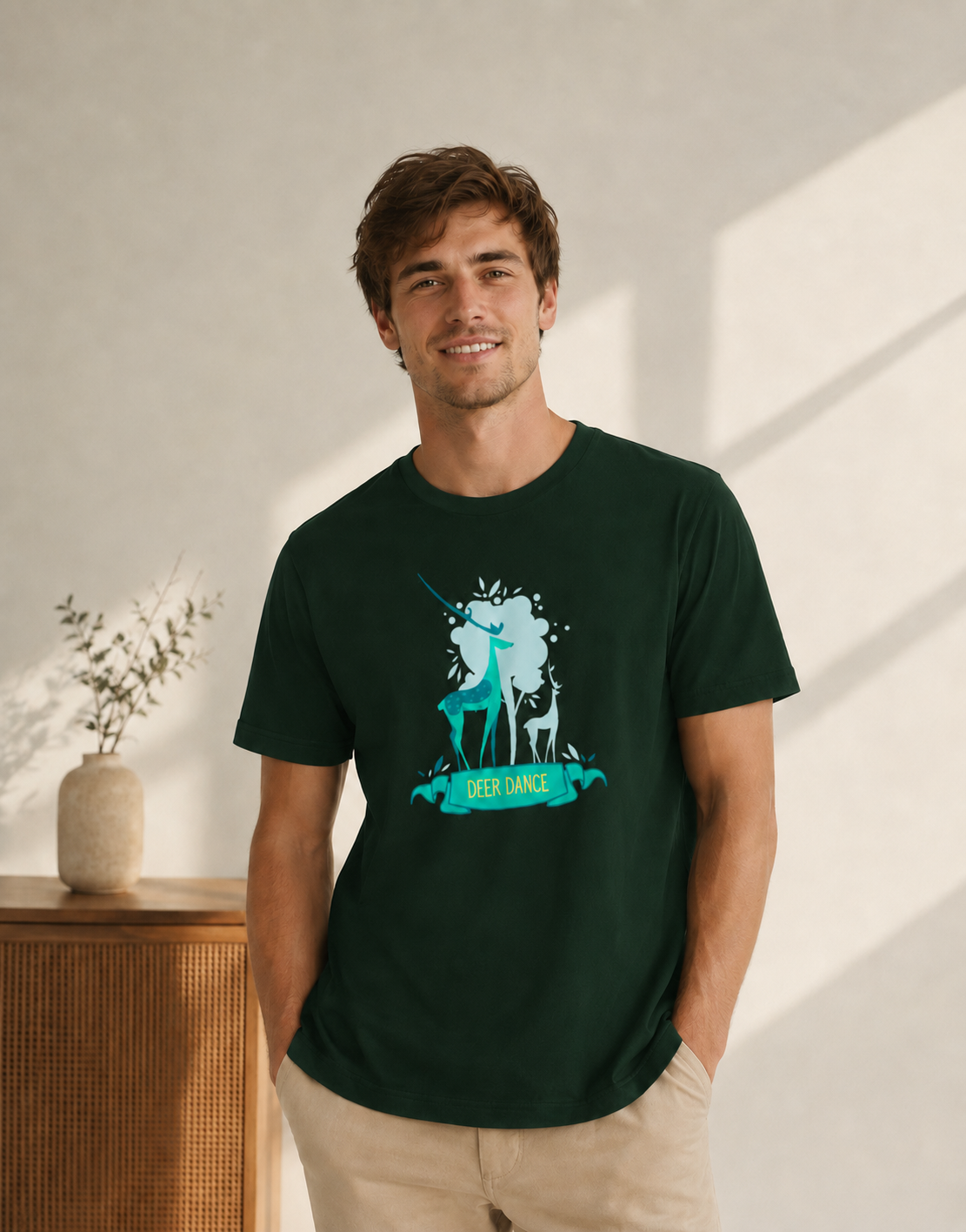 Man wearing a dark green t-shirt with a graphic design of two deer and the text 'Deer Dance' in a bright indoor setting.