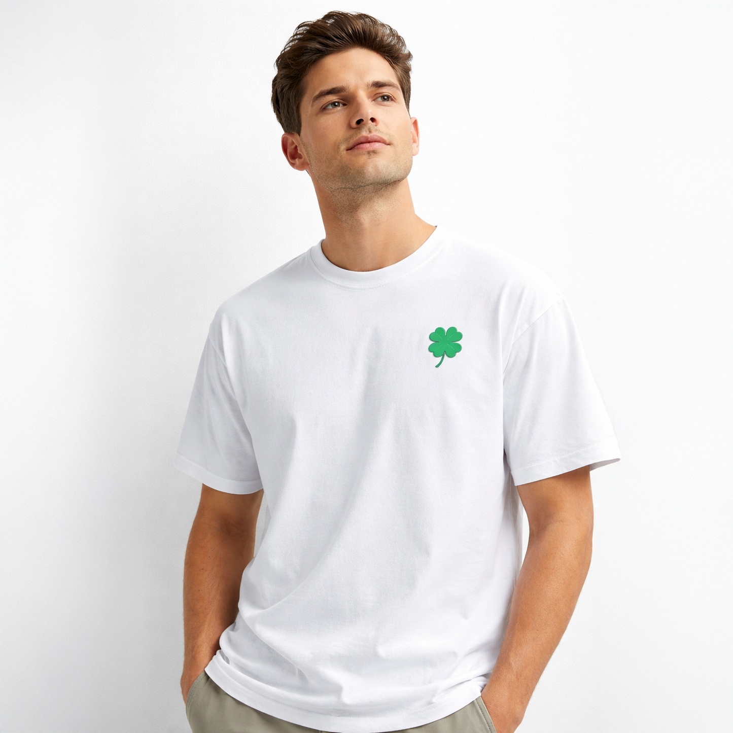 Man wearing a white t-shirt with a green four-leaf clover design on a light gray background