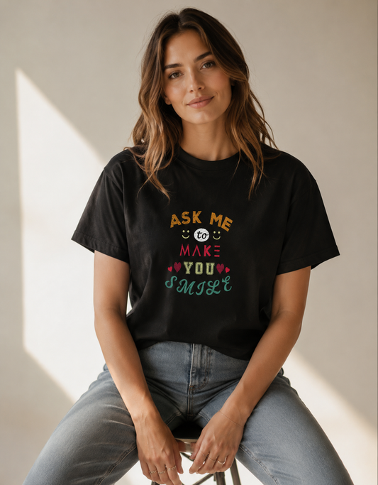 Woman wearing a black t-shirt with colorful text sitting on a stool.