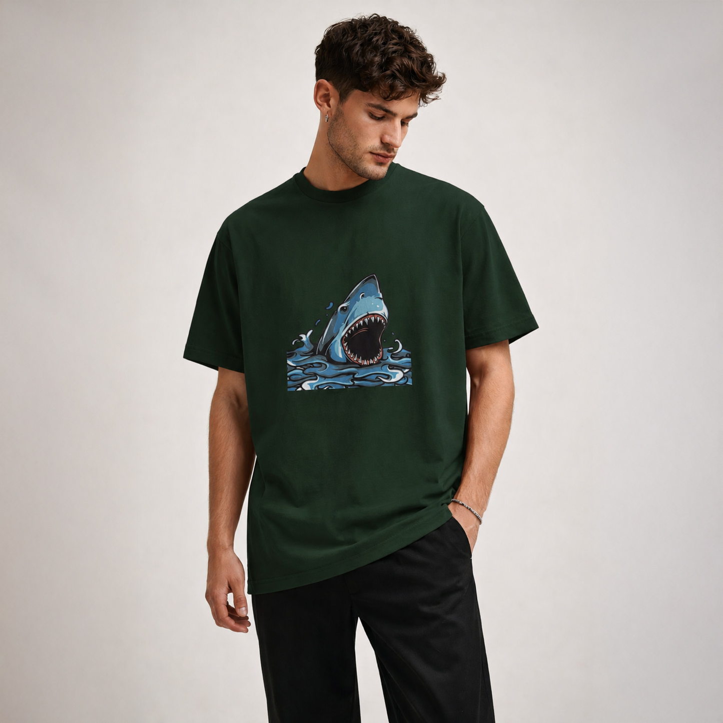 Man wearing a green t-shirt with a shark graphic on a plain background
