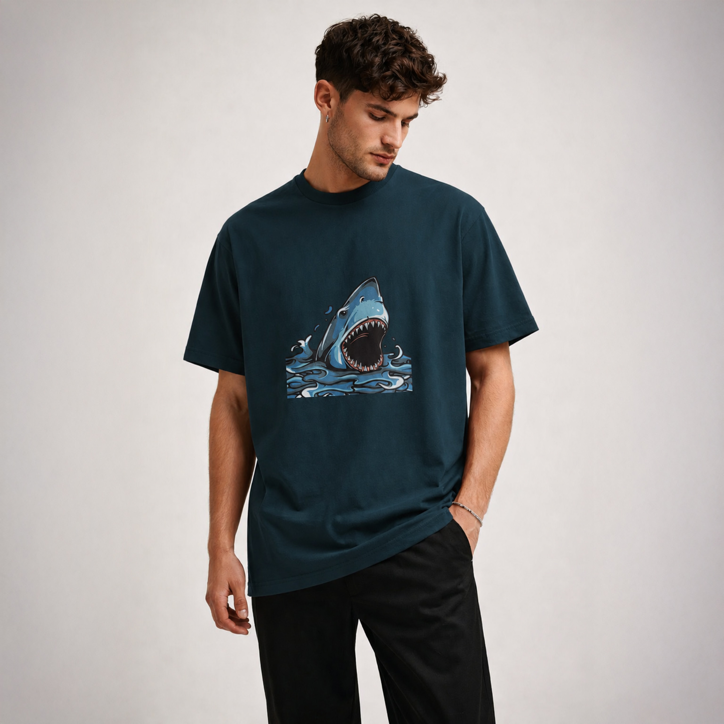 Man wearing a dark green t-shirt with a shark graphic on a light gray background