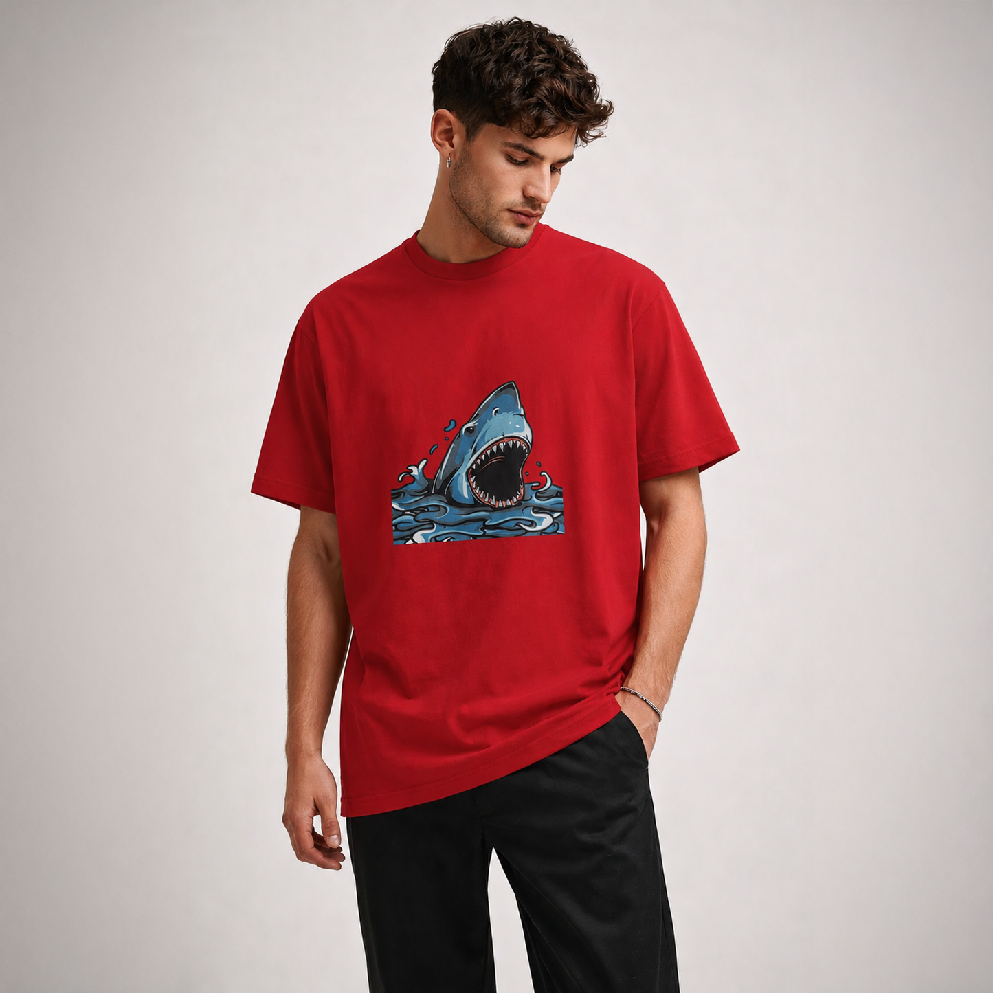 Man wearing a red t-shirt with a shark graphic on a plain background