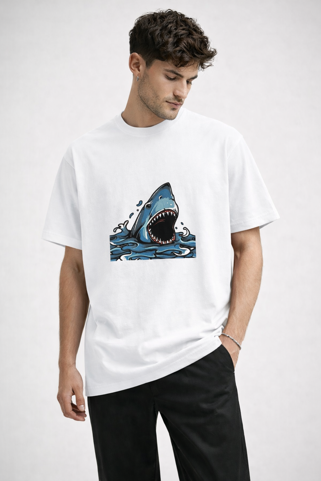 Man wearing a white t-shirt with a shark graphic on a plain background